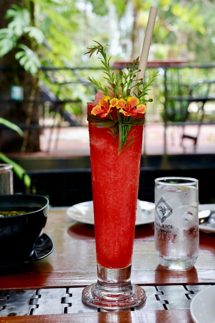 a tall red drink sitting on top of a wooden table
