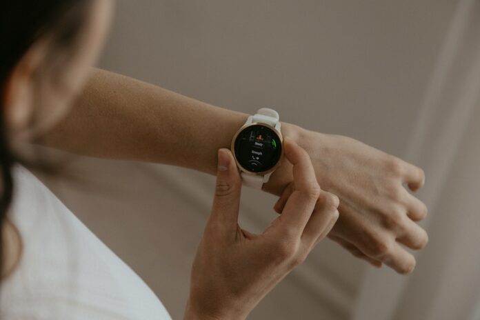 A woman holding a smart watch in her hand